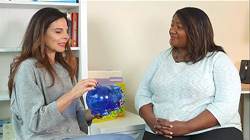 Gail holds a piggy bank and explains emotions to Dawn, the host