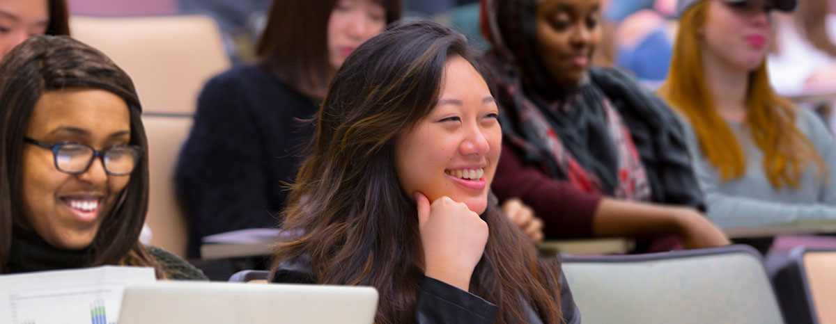 College student in a lecture setting, smiling with fellow class mates College student in a lecture setting, smiling with fellow class mates